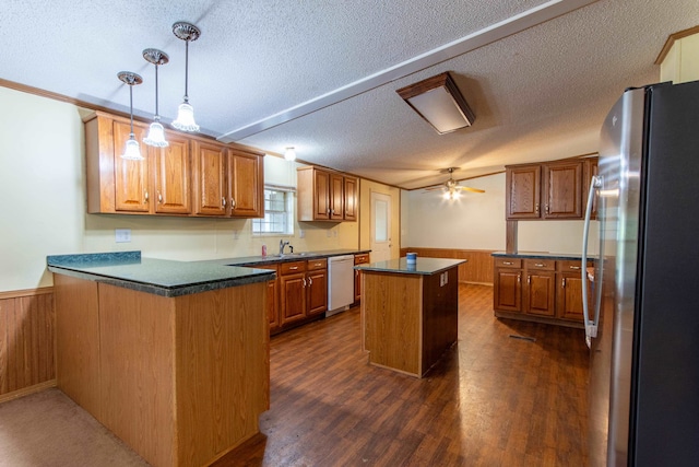 kitchen featuring a textured ceiling, a center island, kitchen peninsula, and stainless steel fridge