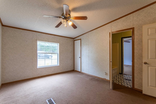 carpeted spare room with a textured ceiling, crown molding, and ceiling fan