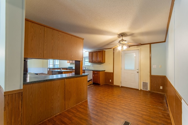 kitchen with dark hardwood / wood-style flooring, kitchen peninsula, ceiling fan, and a textured ceiling