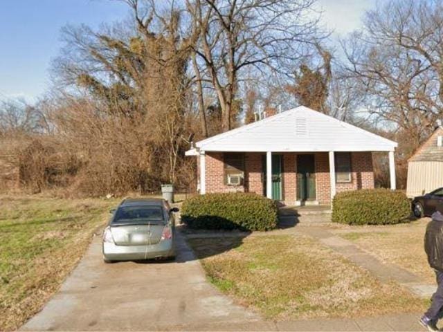 bungalow with brick siding, concrete driveway, and a front lawn