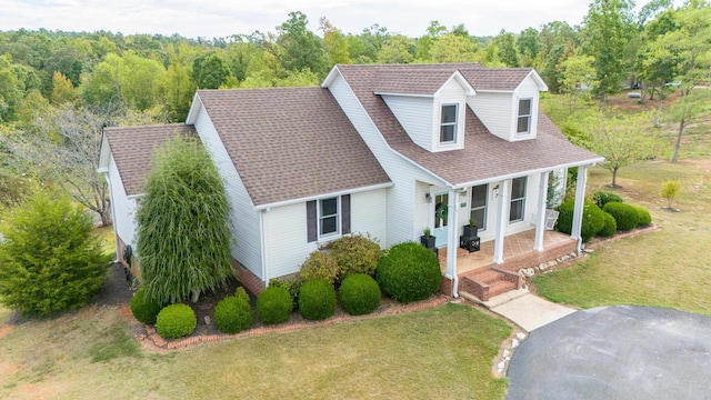 new england style home featuring covered porch and a front lawn