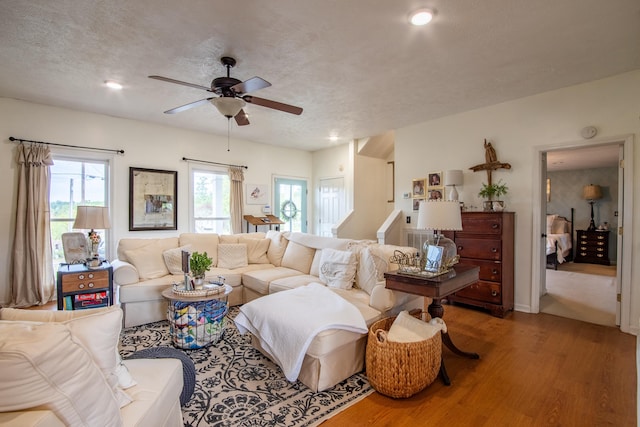 living room featuring hardwood / wood-style floors, ceiling fan, and a textured ceiling