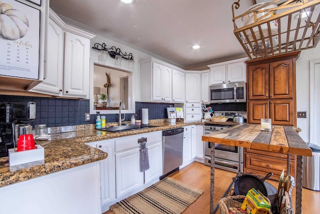 kitchen with white cabinetry, sink, decorative backsplash, appliances with stainless steel finishes, and light hardwood / wood-style floors