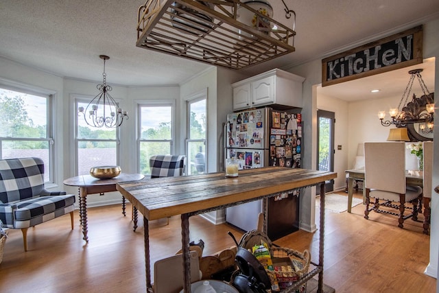 kitchen with light wood-type flooring, an inviting chandelier, and white cabinets