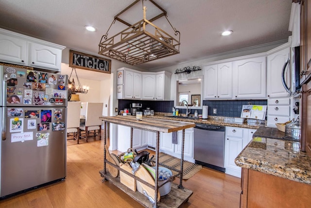 kitchen featuring stainless steel appliances, an inviting chandelier, light wood-type flooring, and white cabinets