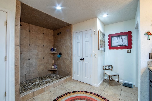 bathroom with tiled shower, vanity, a textured ceiling, and tile patterned floors