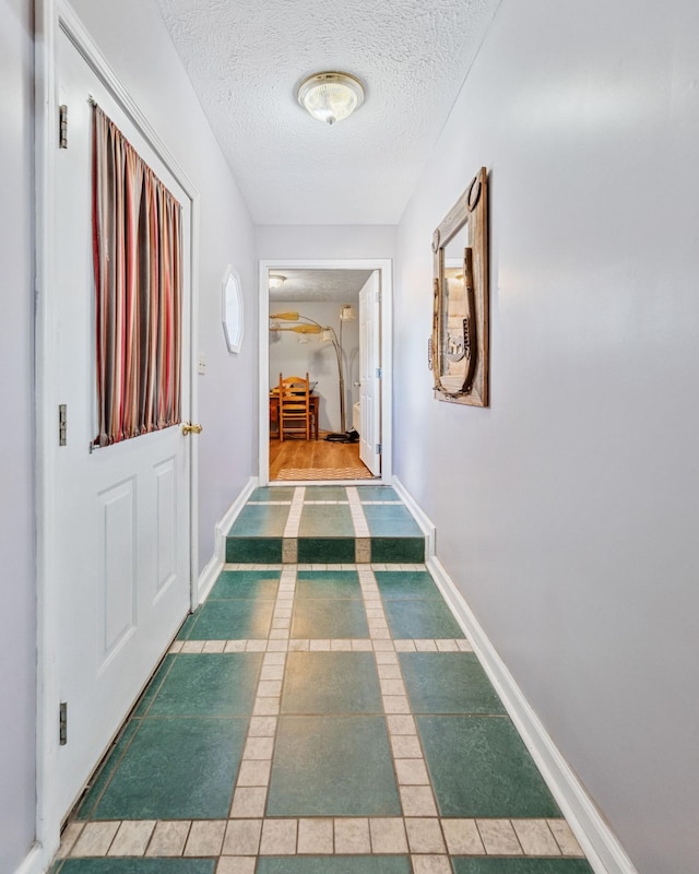 hall featuring a textured ceiling and tile patterned floors