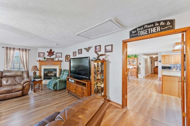 living room with a textured ceiling, a tiled fireplace, and light hardwood / wood-style floors