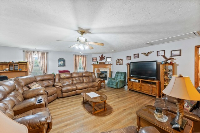 living room featuring ceiling fan, light hardwood / wood-style floors, a textured ceiling, and a healthy amount of sunlight