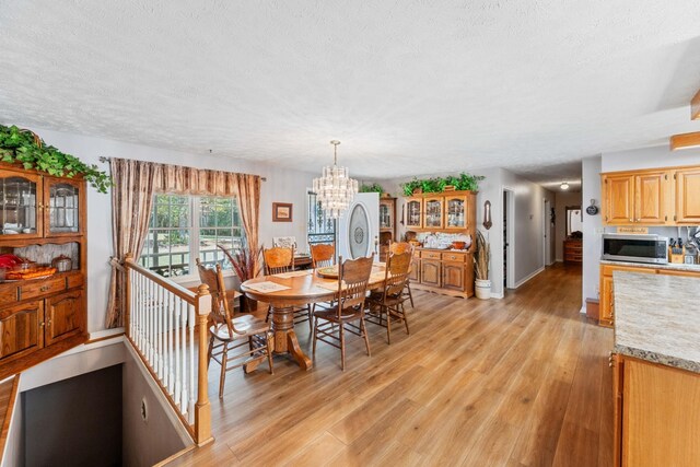 dining room with a textured ceiling, a chandelier, and light hardwood / wood-style floors