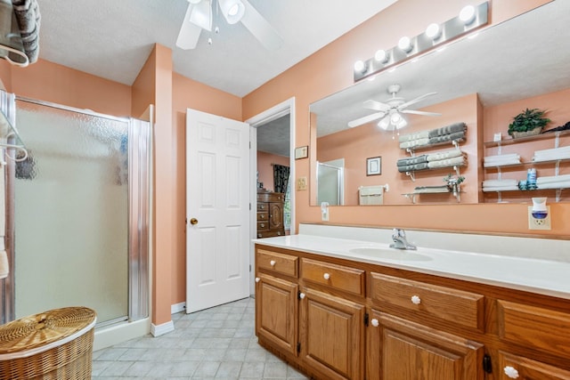 bathroom featuring ceiling fan, baseboards, a stall shower, and vanity