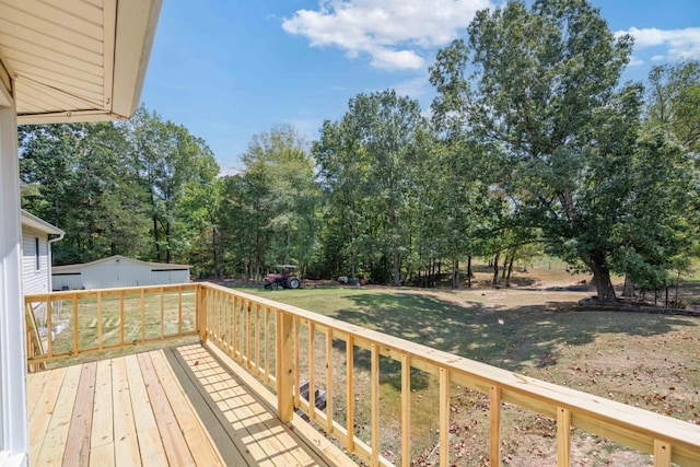 deck with a storage unit, a lawn, and an outdoor structure