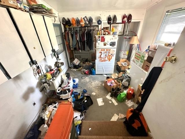 interior space featuring water heater, concrete flooring, and white fridge