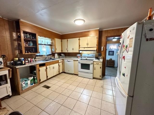 kitchen featuring wood walls, white appliances, sink, and light tile patterned flooring