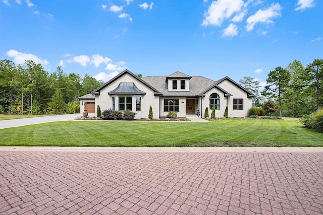 modern farmhouse featuring a front lawn, a garage, driveway, and stucco siding