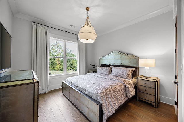 bedroom featuring visible vents, wood finished floors, baseboards, and ornamental molding