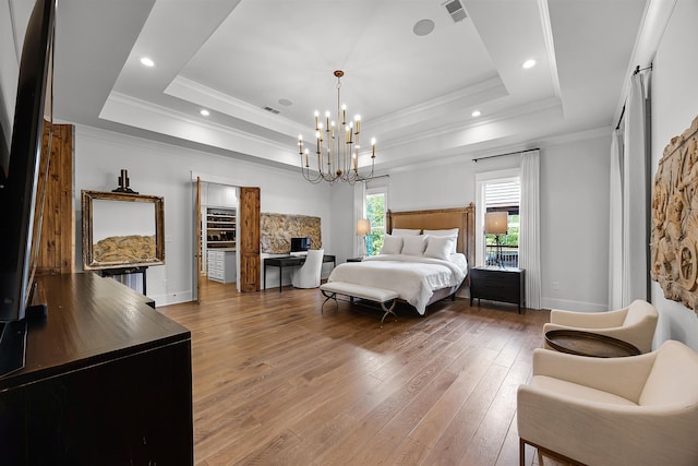 bedroom with visible vents, a tray ceiling, wood-type flooring, crown molding, and a chandelier