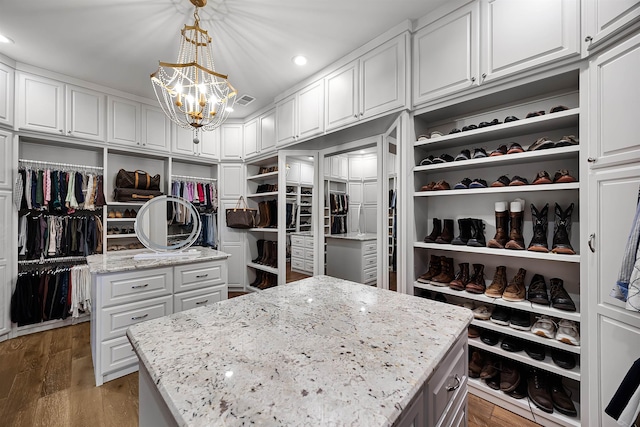 spacious closet featuring wood finished floors, visible vents, and a chandelier