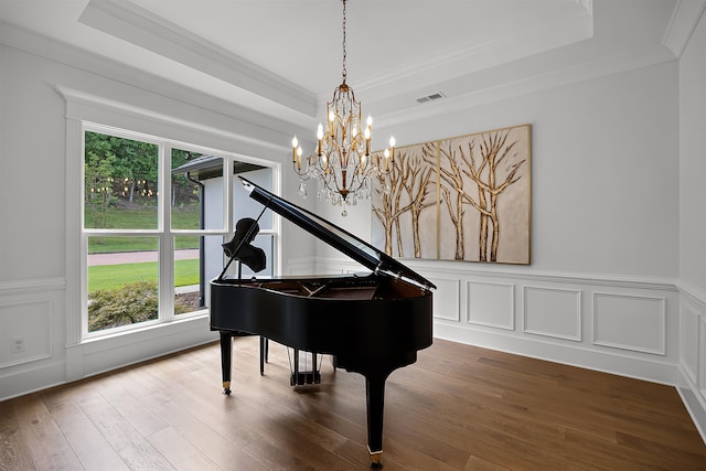 misc room with ornamental molding, hardwood / wood-style floors, a raised ceiling, and a chandelier