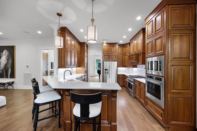 kitchen with light wood-style flooring, appliances with stainless steel finishes, a peninsula, and light countertops