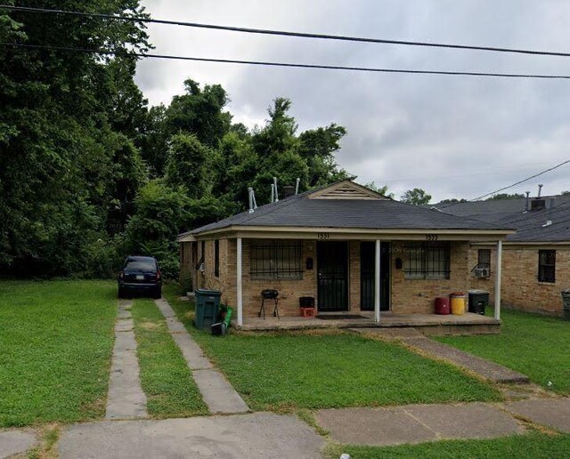 bungalow-style home with brick siding, a front lawn, covered porch, and driveway