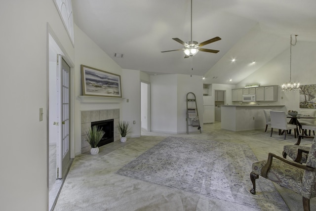 living area with a tiled fireplace, ceiling fan with notable chandelier, visible vents, and high vaulted ceiling