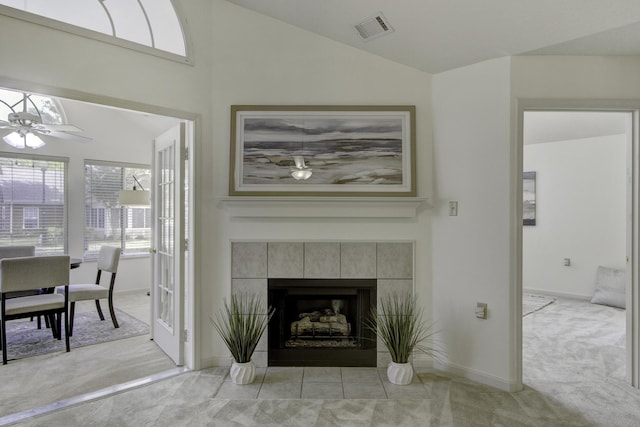 living room with visible vents, ceiling fan, light colored carpet, lofted ceiling, and a tile fireplace