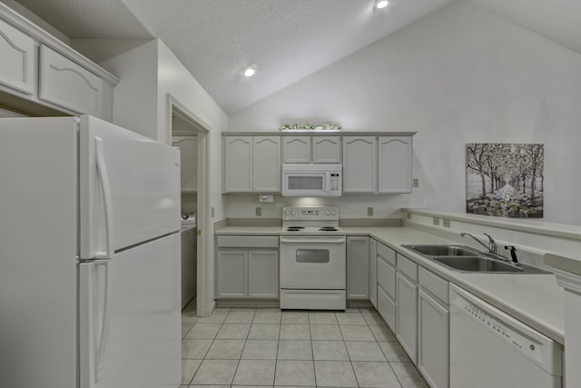 kitchen featuring light countertops, lofted ceiling, light tile patterned floors, white appliances, and a sink