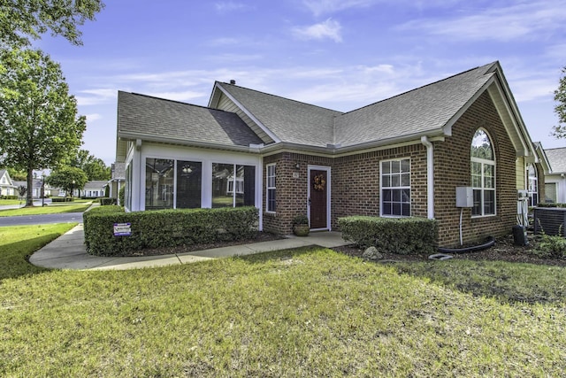 view of front facade featuring brick siding, a shingled roof, and a front yard