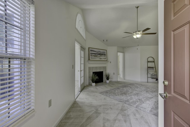 unfurnished living room with baseboards, carpet floors, high vaulted ceiling, a tile fireplace, and ceiling fan