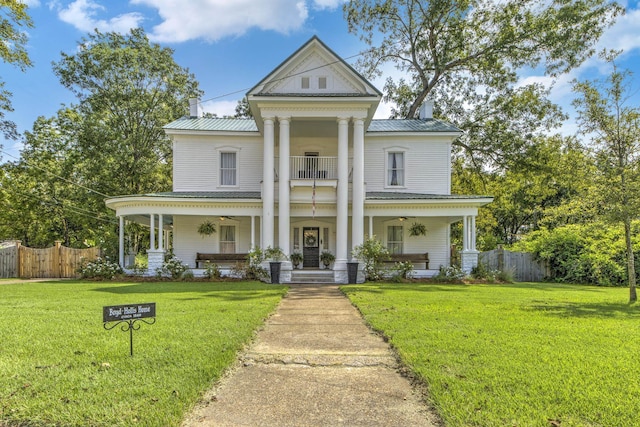 greek revival inspired property with covered porch, a balcony, and a front yard