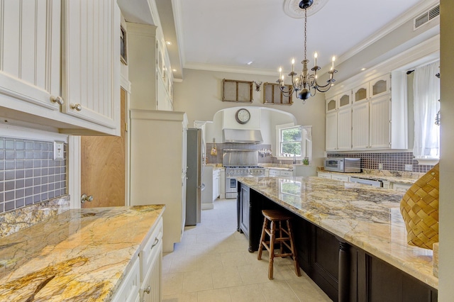 kitchen with pendant lighting, light stone counters, backsplash, and white cabinets