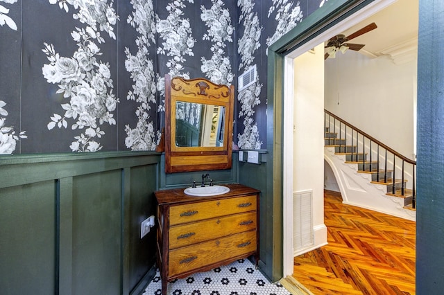 interior space with crown molding, vanity, ceiling fan, and parquet flooring