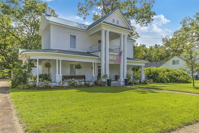 greek revival house featuring a porch and a front lawn