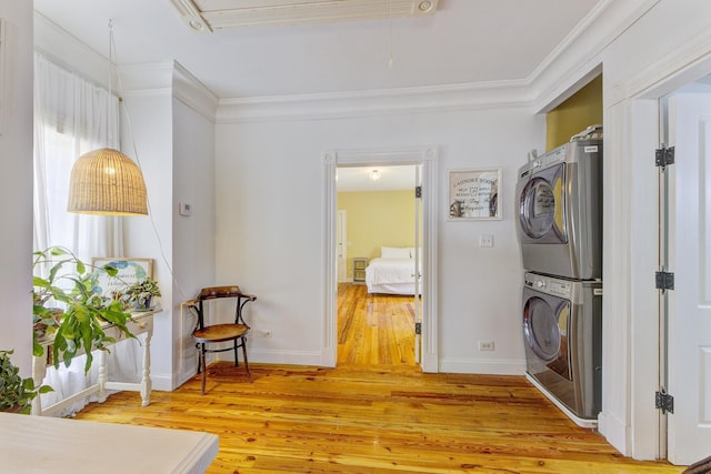 laundry room with crown molding, wood-type flooring, and stacked washer and clothes dryer