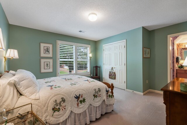 carpeted bedroom featuring a closet, connected bathroom, and a textured ceiling