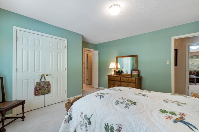 bedroom featuring light carpet, a textured ceiling, and a closet