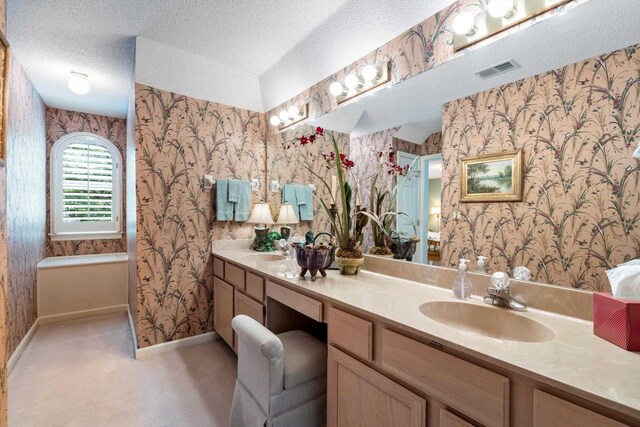 bathroom featuring a textured ceiling, vanity, and a tub to relax in