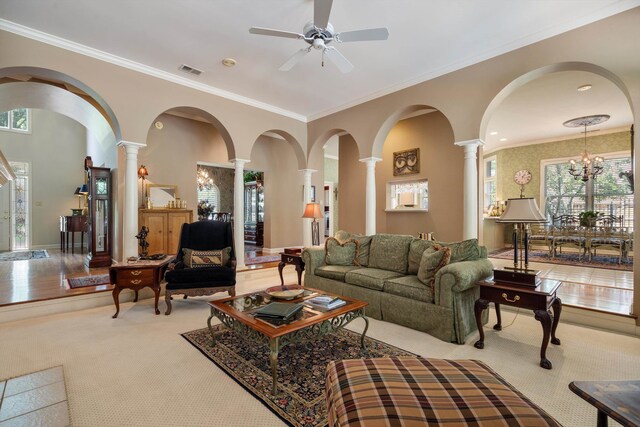 living room featuring light wood-type flooring, ceiling fan with notable chandelier, decorative columns, and crown molding