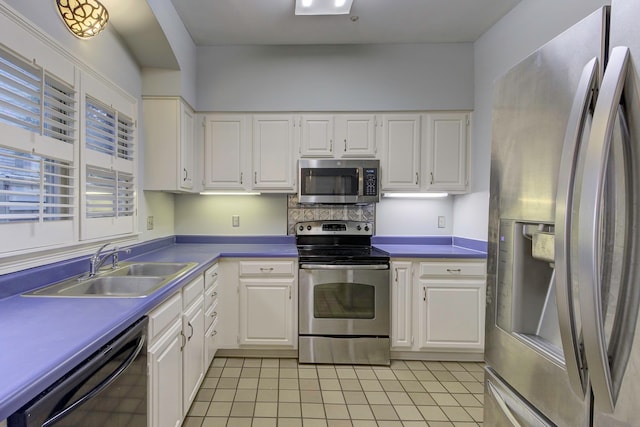 kitchen with sink, appliances with stainless steel finishes, white cabinets, and light tile patterned flooring