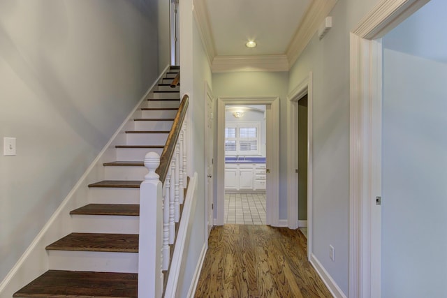 staircase with crown molding, hardwood / wood-style flooring, and sink