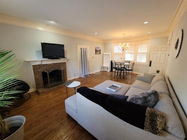 living room with a fireplace, crown molding, wood-type flooring, and an inviting chandelier