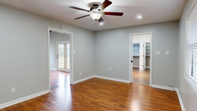 spare room featuring a healthy amount of sunlight, ceiling fan, hardwood / wood-style floors, and french doors