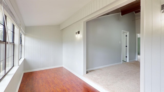 spare room featuring lofted ceiling, plenty of natural light, and hardwood / wood-style flooring