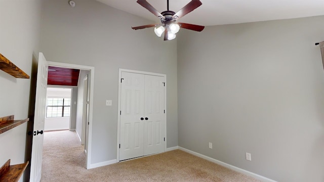 interior space with high vaulted ceiling, a closet, ceiling fan, and light carpet