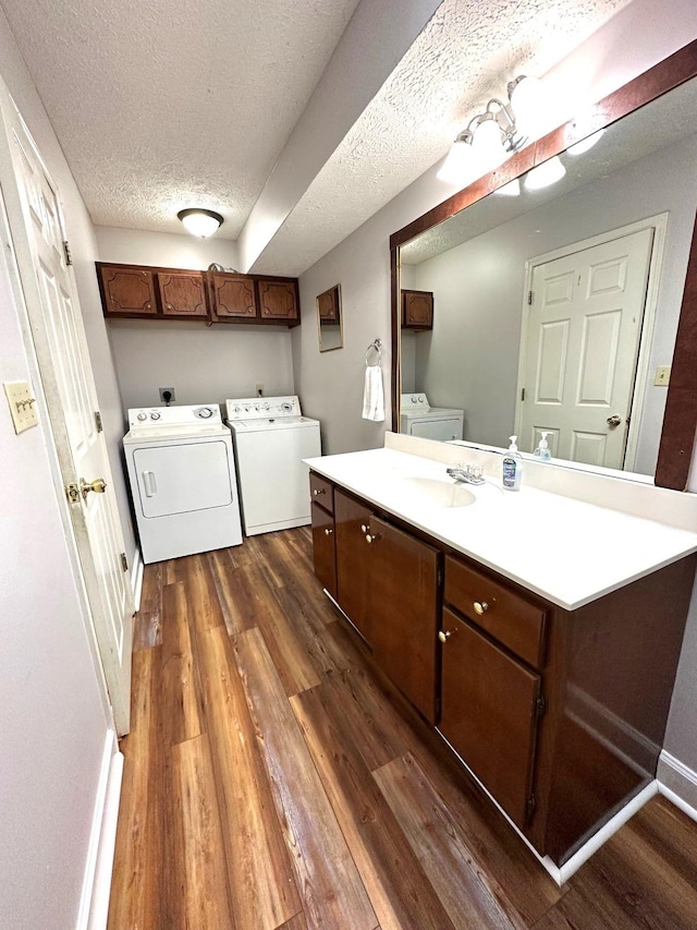 bathroom with a textured ceiling, vanity, hardwood / wood-style floors, washing machine and clothes dryer, and toilet