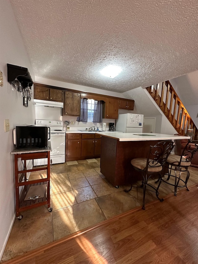 kitchen featuring a textured ceiling, light wood-type flooring, and white appliances