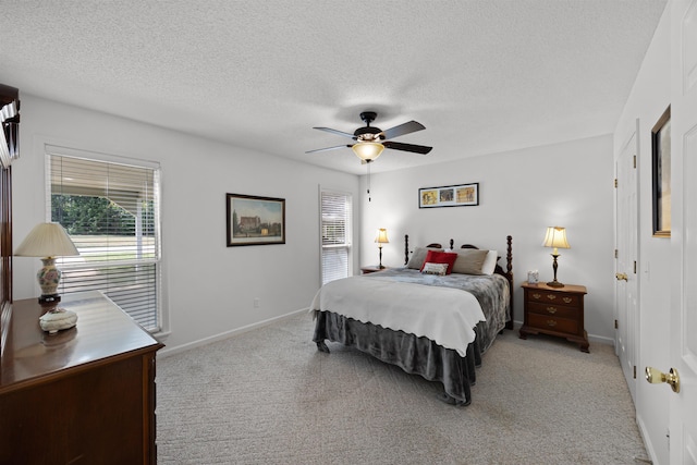 bedroom featuring a textured ceiling, light colored carpet, and ceiling fan