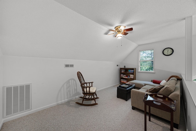 living area featuring a textured ceiling, carpet flooring, ceiling fan, and vaulted ceiling