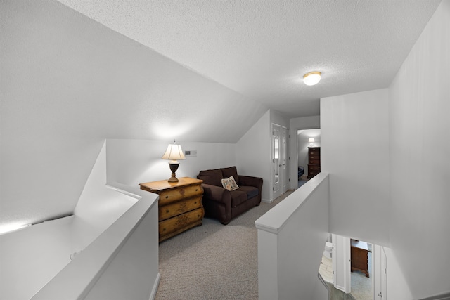 interior space featuring lofted ceiling, light colored carpet, and a textured ceiling